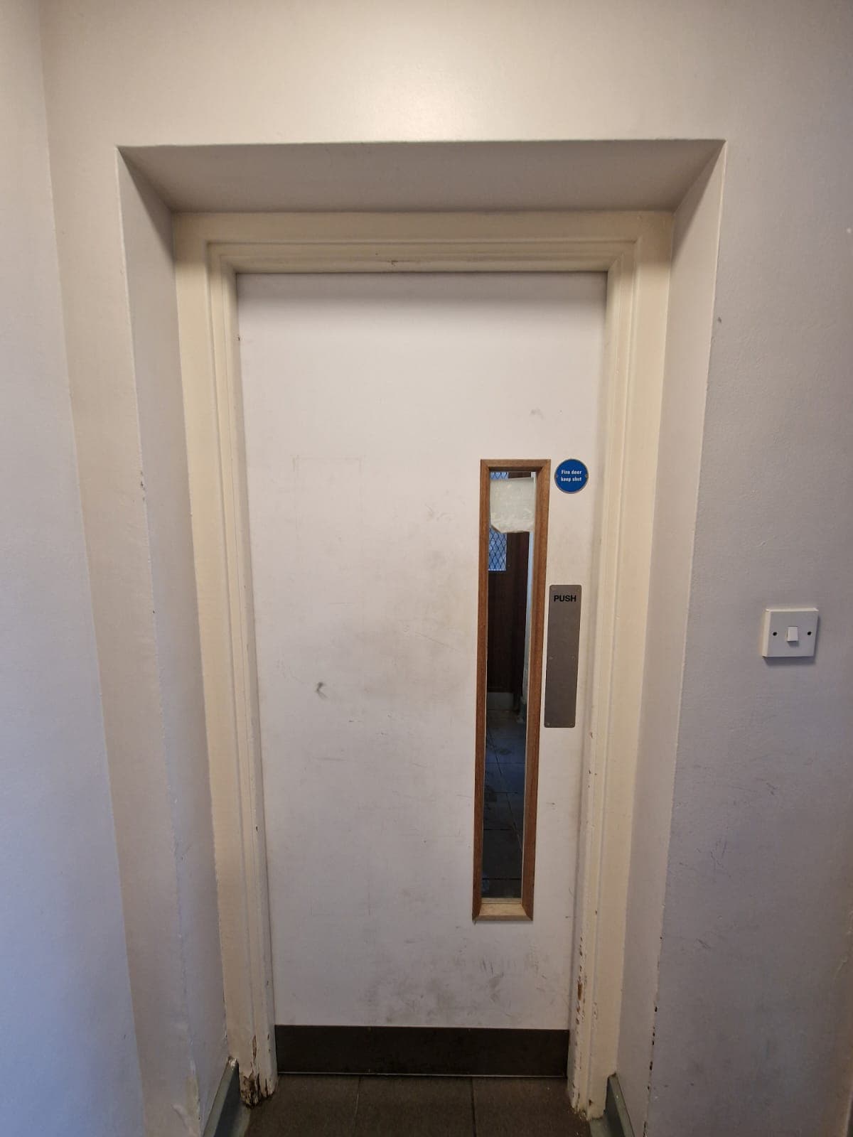 Dirty communal hallway in residential block London showing scuff marks, dirt buildup, and unclean door surface