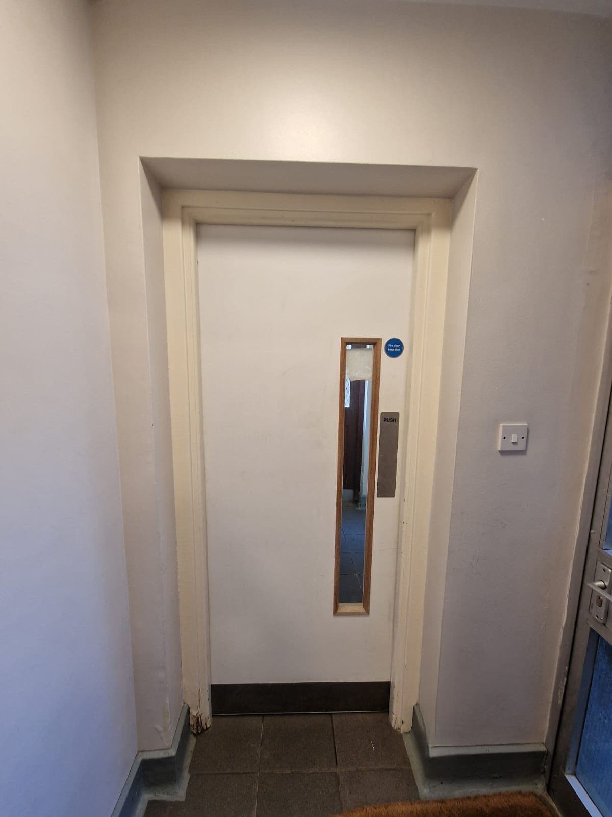 Clean communal hallway in residential block London after professional cleaning with spotless door and floor